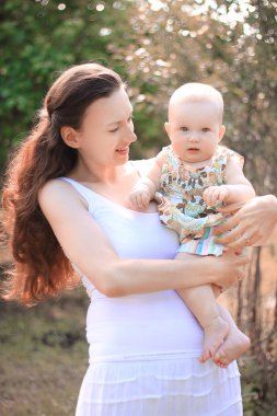 Çekici genç anne kollarında küçük bir kız tutarak