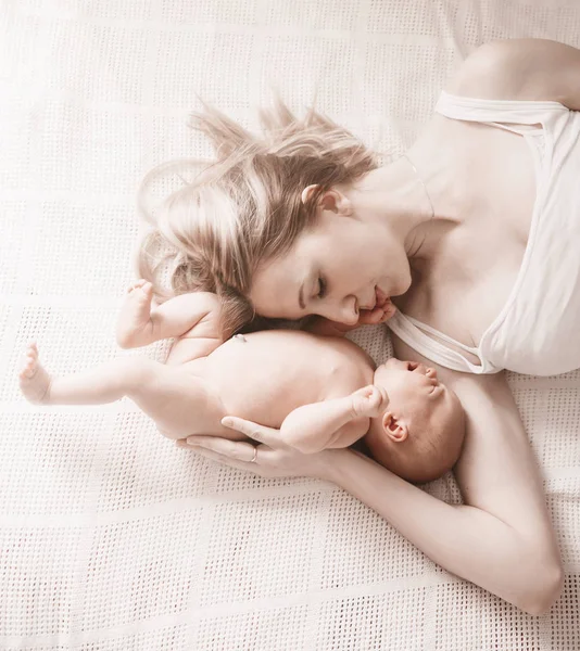 Mãe feliz com a filha recém-nascida deitada na cama — Fotografia de Stock
