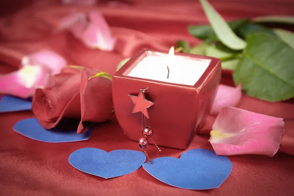 Vela y rosa sobre fondo de seda roja — Foto de Stock