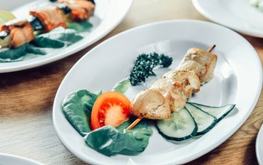 kebap ve masanın üzerine beyaz bir plaka üzerinde taze sebze