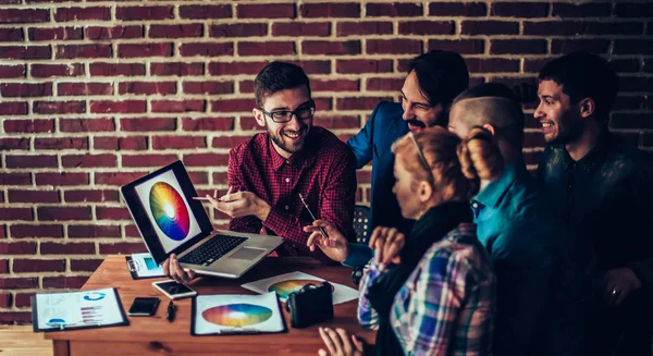 team of designers in the workplace in front of an open laptop di