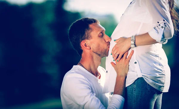 Marido feliz abrazando a su esposa embarazada en un paseo por el parque — Foto de Stock