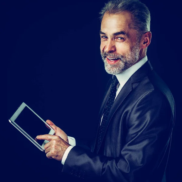 Erfahrener Geschäftsmann mit digitalem Tablet auf schwarzem Hintergrund. — Stockfoto