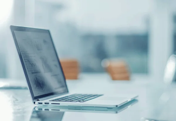 laptop with financial graph on the screen at the workplace of th