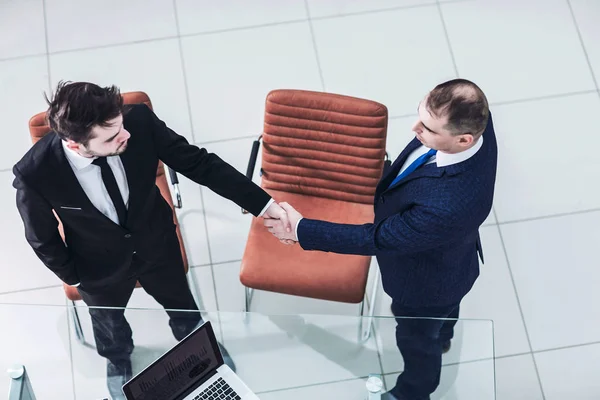 Handshake affärspartners nära skrivbordet, i det rymliga kontoret — Stockfoto