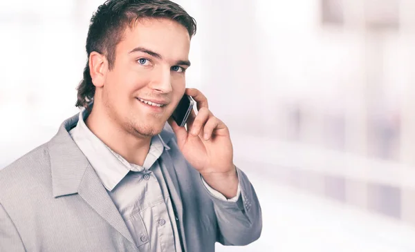 Uomo d'affari di successo che parla al telefono. foto un ufficio luminoso . — Foto Stock
