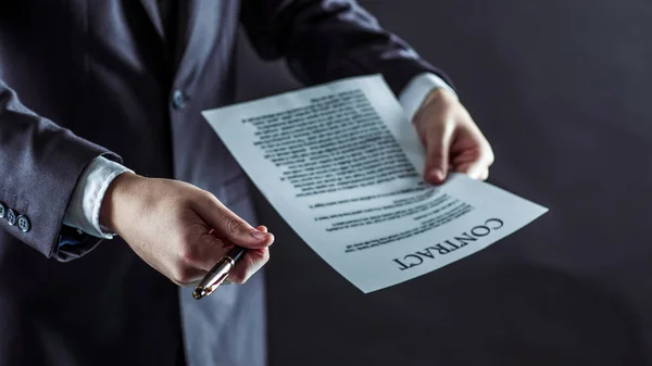 Primer plano de un hombre de negocios sosteniendo una pluma y un documento con las condiciones del contrato . — Foto de Stock