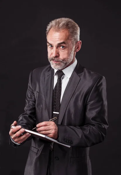 Successful businessman with pen and papers ready for signature on a black background — Stock Photo, Image
