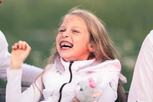 Boldog kis lány ül egy padon puha játék — Stock Fotó