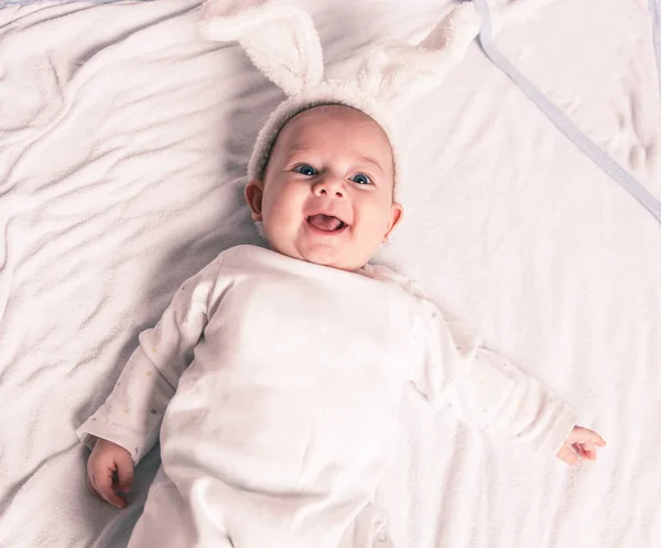 Retrato de adorable bebé sonriente en traje de conejo se encuentra en la cuna — Foto de Stock
