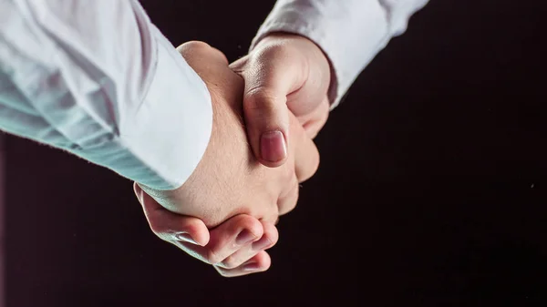 可靠的伙伴关系的概念︰ 握手的商业伙伴在黑色背景上的一个特写镜头. — 图库照片