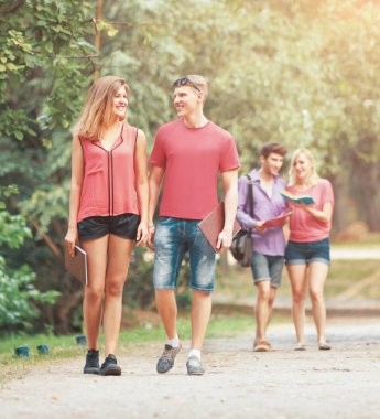 güneşli bir parkta mutlu öğrenci grubu..