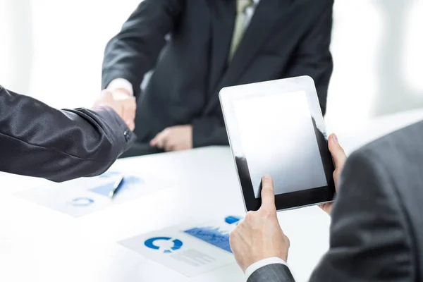 Affärsman med en digital tablett på bakgrunden av ett handslag av affärspartners — Stockfoto