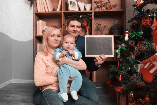 Fiatal, boldog szülők mutatja üres karácsonyi kártya — Stock Fotó