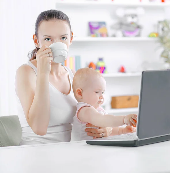 Jovem mãe com pequeno bebê sentado no Desk.the conceito de freelancer — Fotografia de Stock