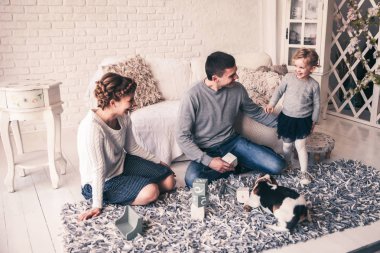 mutlu aile geniş oturma odasında bir evcil köpek ile oynarken