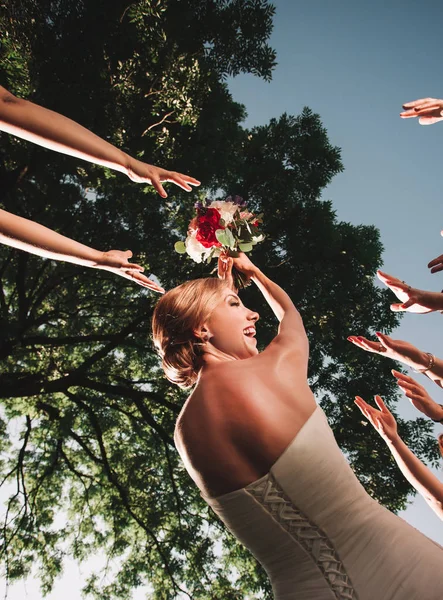 Novia sonriente lanza el ramo de bodas de sus amigos — Foto de Stock