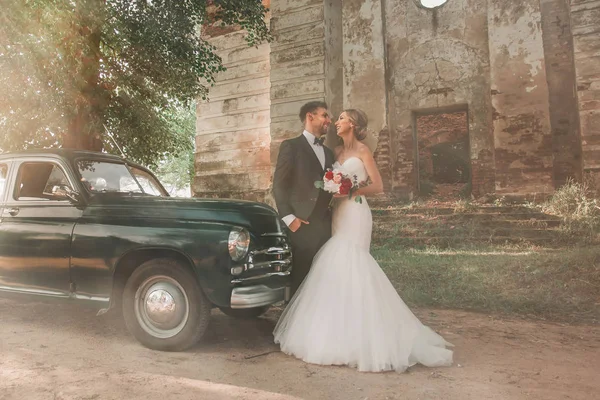 ヴィンテージカーの近くに立つ幸せな花嫁と新郎 — ストック写真