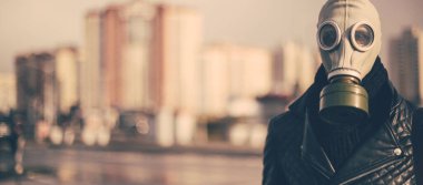 Gaz maskeli sıradan bir genç adam kameraya bakıyor.