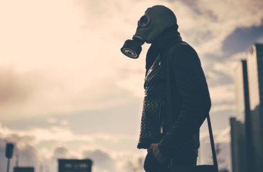 Boş bir şehirde sokakta duran gaz maskeli sıradan bir genç adam.