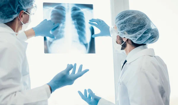Kapat. Koruyucu maskeli bilim adamları akciğerlerin röntgenine bakıyor. . — Stok fotoğraf