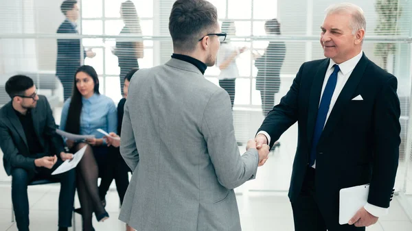 Empresarios se dan la mano de pie en la sala de conferencias . — Foto de Stock