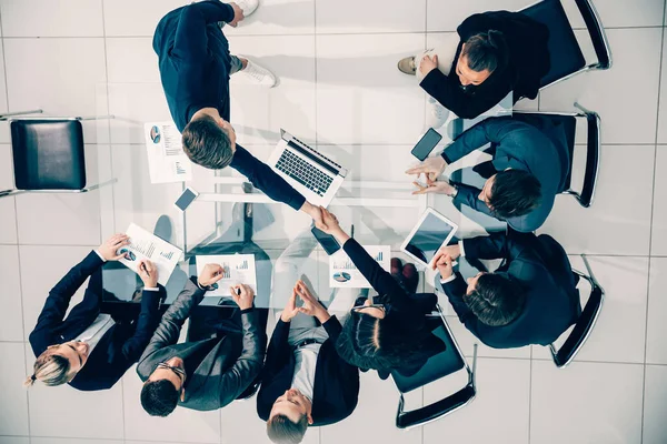 Vista superior. apretón de manos de los empleados felices en una reunión de trabajo . — Foto de Stock