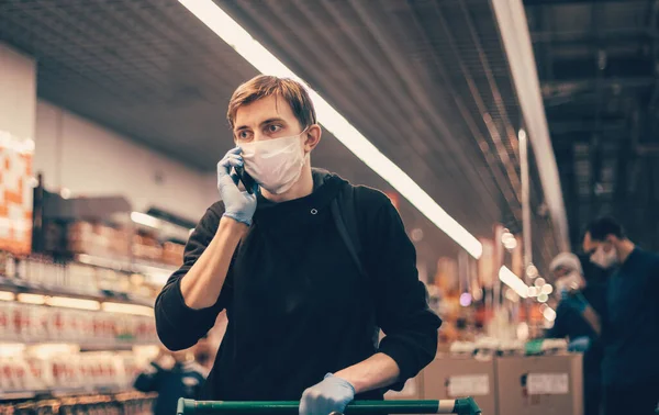 De près. jeune homme dans un masque de protection parlant sur son smartphone. — Photo