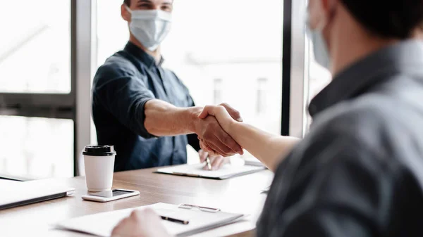 Jonge zakenpartners in beschermende maskers schudden handen met elkaar. — Stockfoto