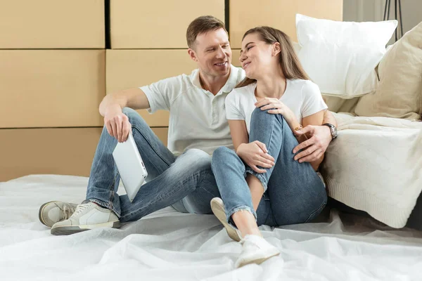 Feliz pareja sentada cerca de cajas en un nuevo apartamento — Foto de Stock