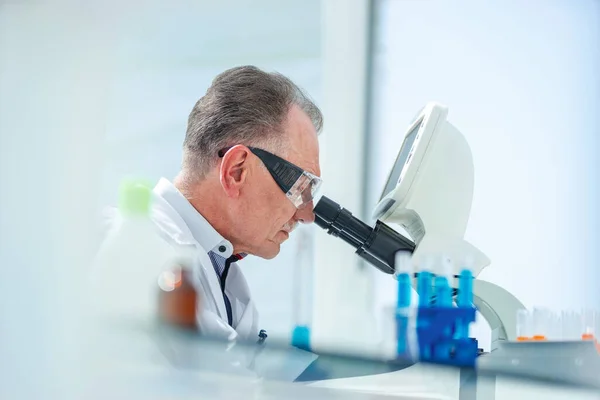 De cerca. científico mirando cuidadosamente a través de un microscopio. — Foto de Stock