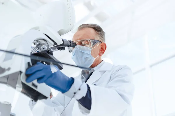 De cerca. un científico serio utilizando un microscopio de laboratorio. — Foto de Stock