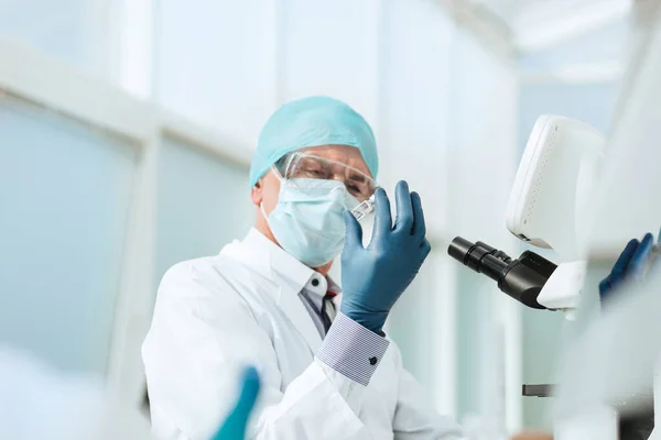 Científico con una ampolla sentada en una mesa de laboratorio . — Foto de Stock