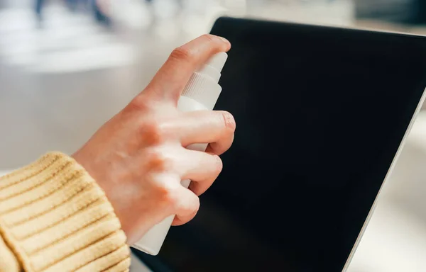 Vicino. la donna che spruzza lo spray sullo schermo del computer portatile — Foto Stock