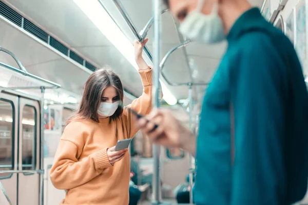 Pessoas com smartphones em pé em um carro de metrô. — Fotografia de Stock