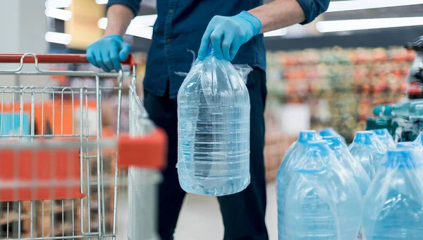 Man in protective gloves with a bottle of drinking water. — Stock Photo, Image