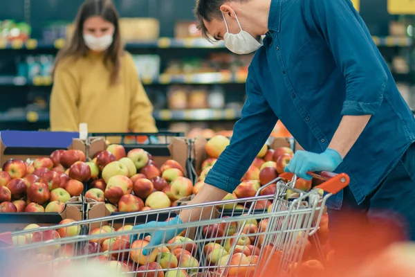 Homme et une femme en masques de protection faisant leurs courses dans un supermarché. — Photo