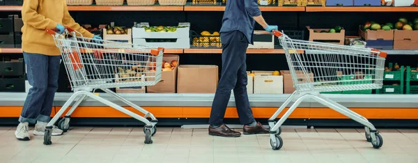 Karantina döneminde süpermarkette alışveriş arabalı bir adam ve bir kadın..