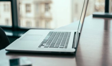 Yan görünüş. Ofis masasında dizüstü bilgisayar aç.