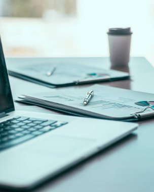 Kapat. Masaüstünde bir dizüstü bilgisayar ve finansal grafik.