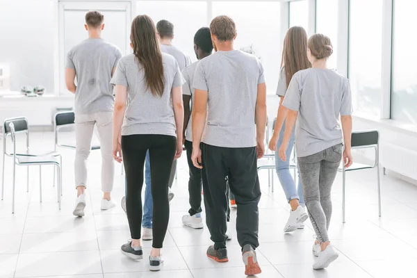 Vista trasera. un equipo de jóvenes que pasan por la oficina de la luz — Foto de Stock