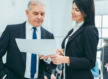 Patron ve yardımcısı bir iş belgesini tartışıyor.