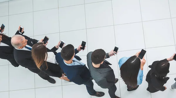 Vista dall'alto. un gruppo di uomini d'affari che guardano i loro schermi smartphone. — Foto Stock