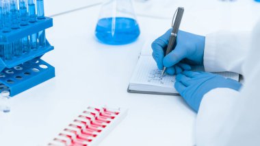 Kapat. Bilim adamı virolog defterine not alıyor. .