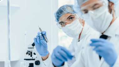 Kapat. Laboratuvarda çalışan koruyucu giysili bir grup bilim adamı..