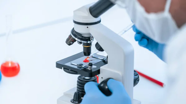 De cerca. científico usando un microscopio para estudiar la sangre . — Foto de Stock