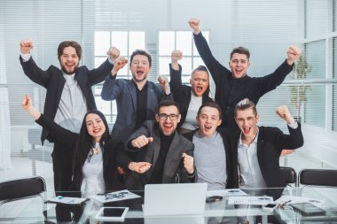 Ofis masasında oturan bir grup mutlu çalışan.
