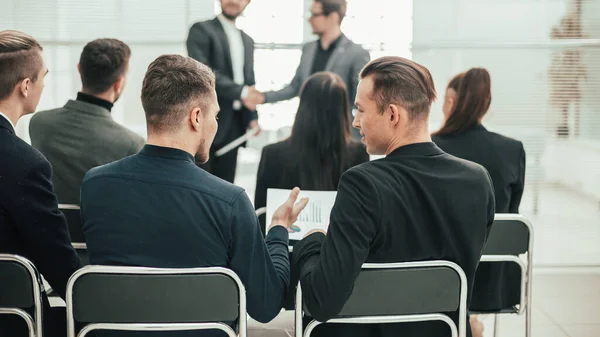 back view. group of employees sitting in a conference room.