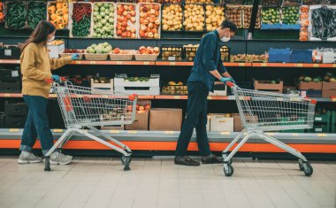 Karantina döneminde süpermarkette alışveriş arabalı bir adam ve bir kadın..