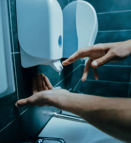 close up. young man pushing a dispenser with bactericidal soap.